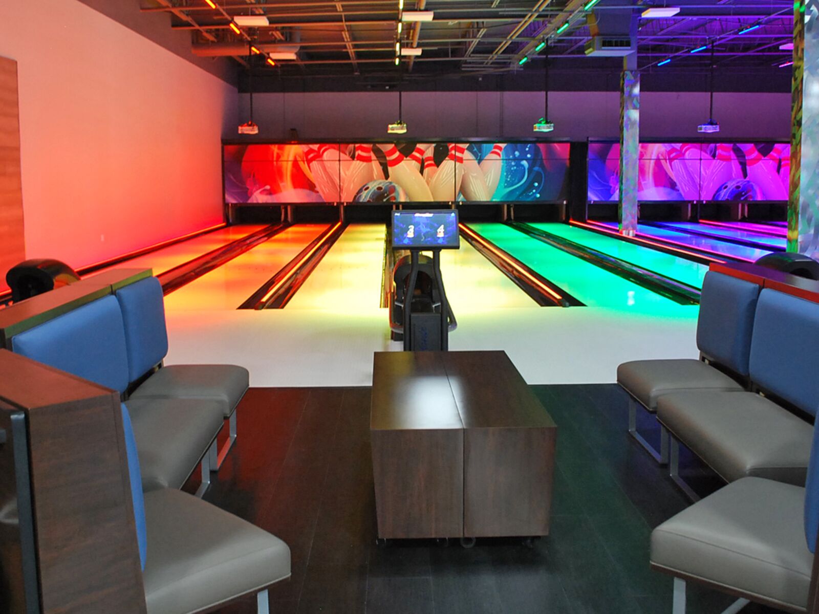 The bowling lanes at GameTime Daytona lit red, green and blue, with booth seating and tables for each lane in front