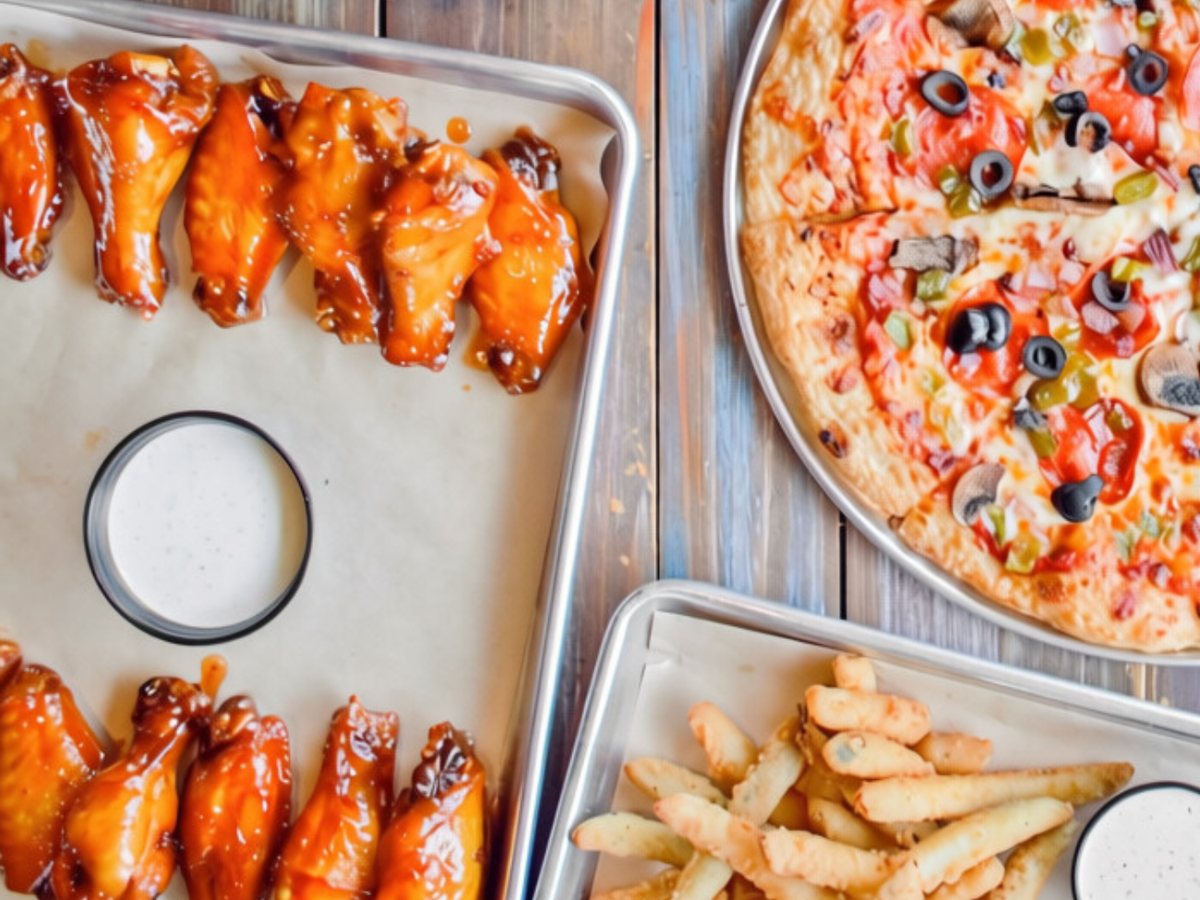 Jumbo bone-in wings on a tray with a ranch dip, beside a tray of fries