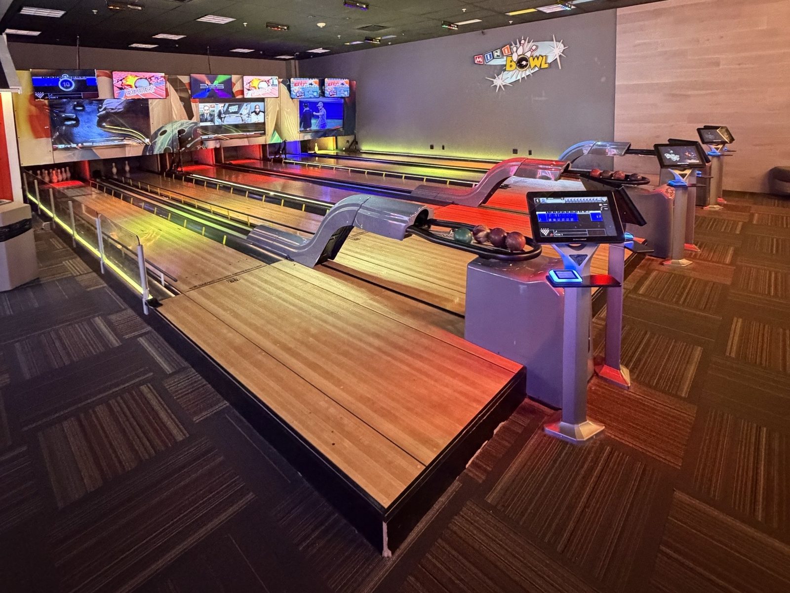 The mini bowling lanes at GameTime Fort Myers, lit orange and blue, with the scoring screens above the pins