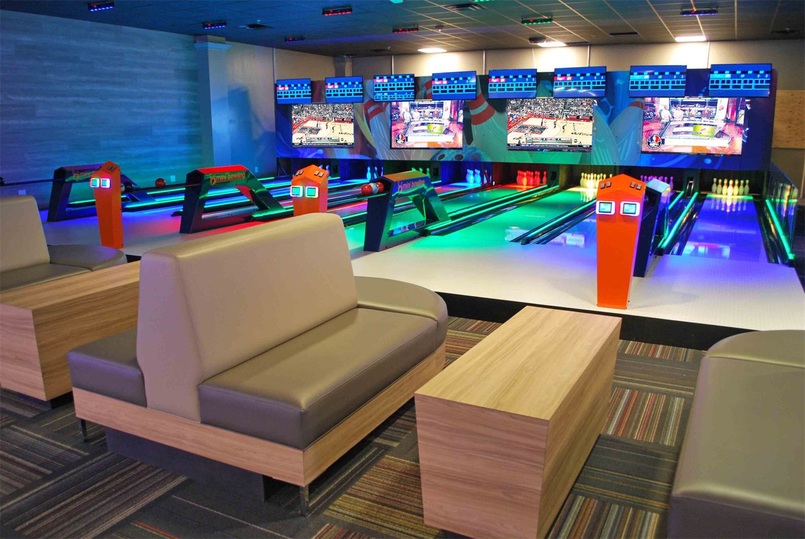The mini bowling lanes at GameTime Ocoee, lit blue and green, with lounge seating in front