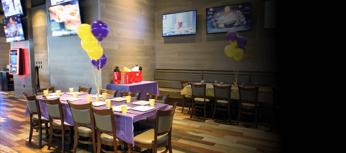 Party tables with balloons under screens in the restaurant at GameTime Fort Myers