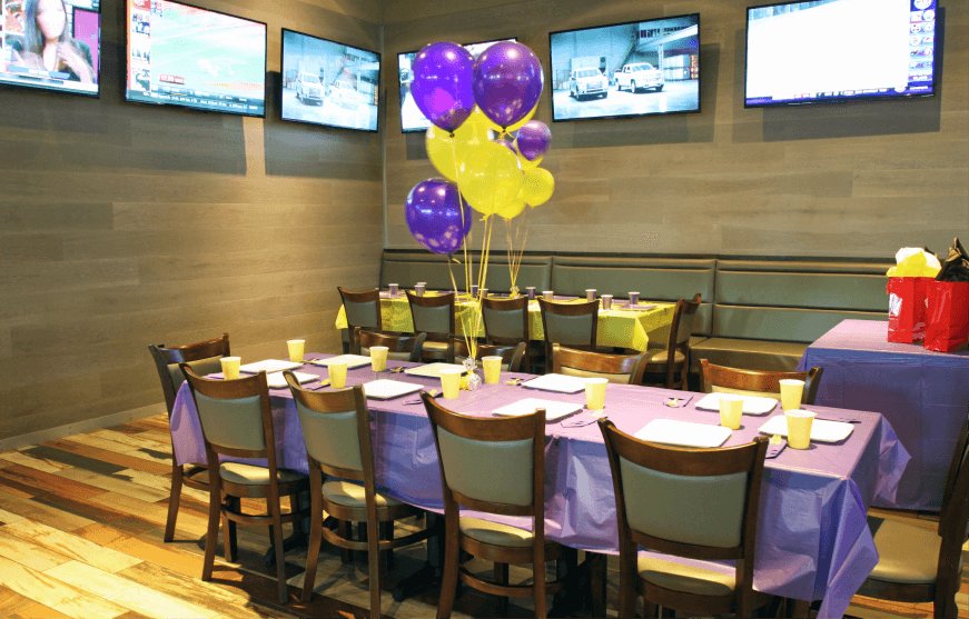 A long party table set with purple cloths and balloon bunches at GameTime Fort Myers