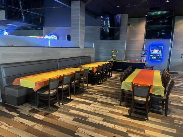 Booth and table seating set with yellow, orange and green cloths at GameTime Fort Myers, with the game floor beyond