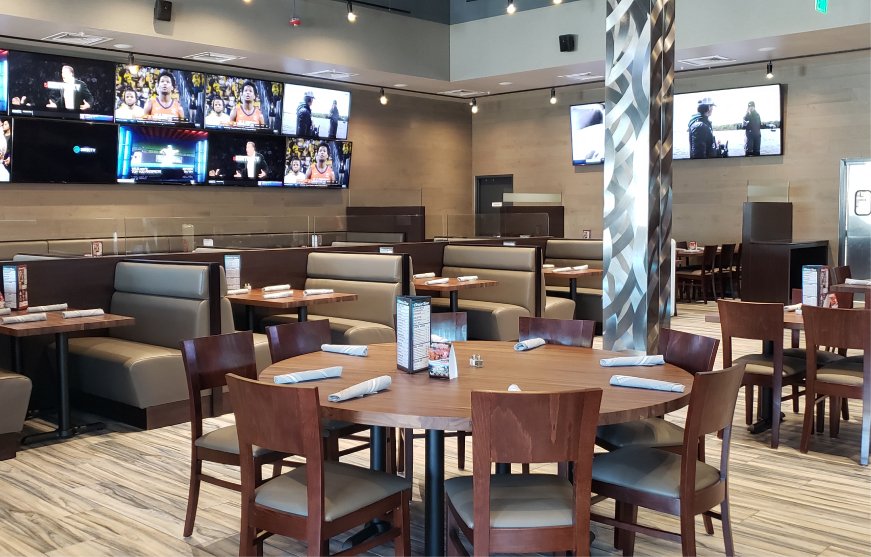 Round tables set with menus in the restaurant space at GameTime Kissimmee