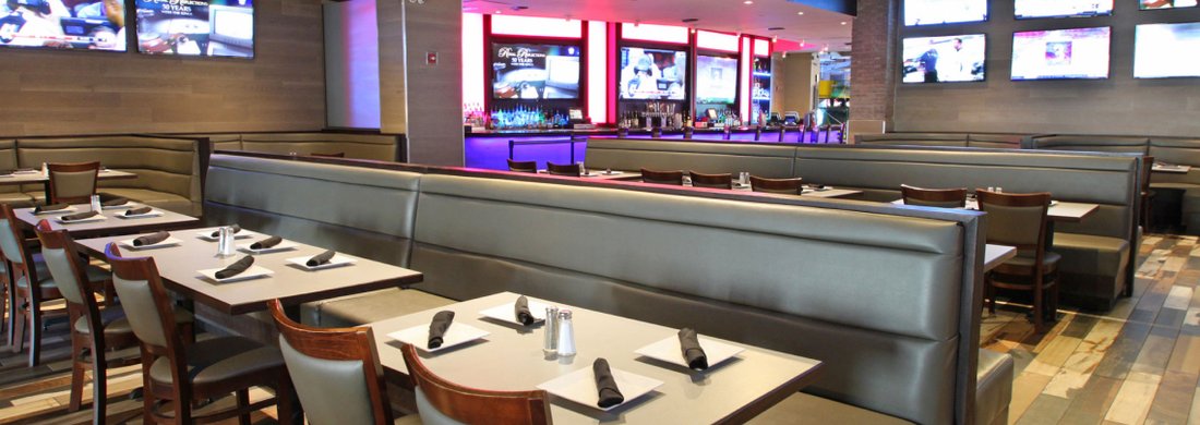 Booth seating under a wall of screens in the downstairs restaurant at GameTime Miami