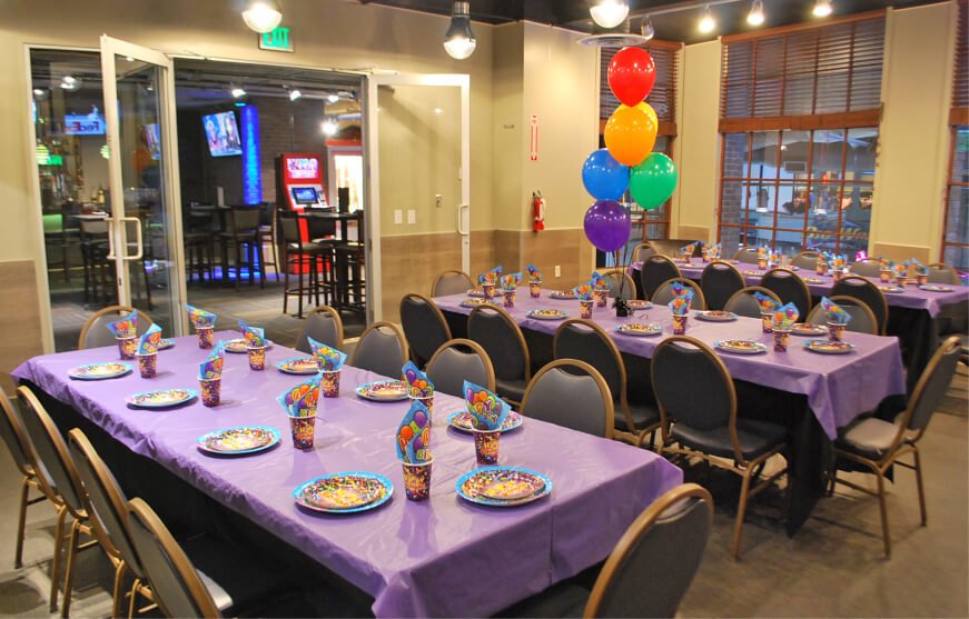 Long tables set with purple cloths and balloons in the event space at GameTime Miami