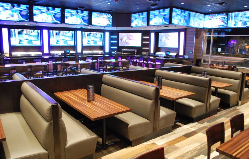Booth seating along a wall of screens in the restaurant space at GameTime Ocoee