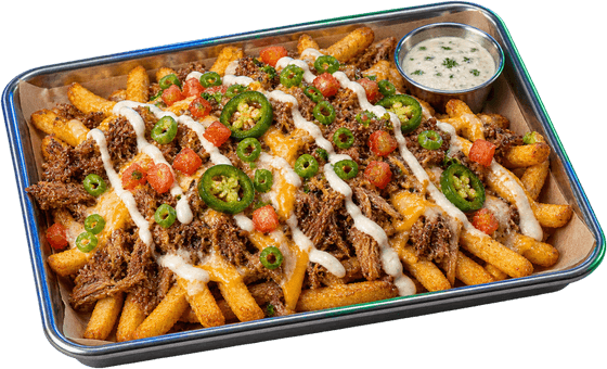 A tray of fries loaded with carnitas, melted cheese, jalapeños, tomato and a drizzle of white sauce, with a cup of dipping sauce