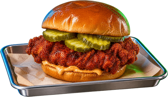 A Nashville hot chicken sandwich with pickles on a brioche bun, on a metal tray